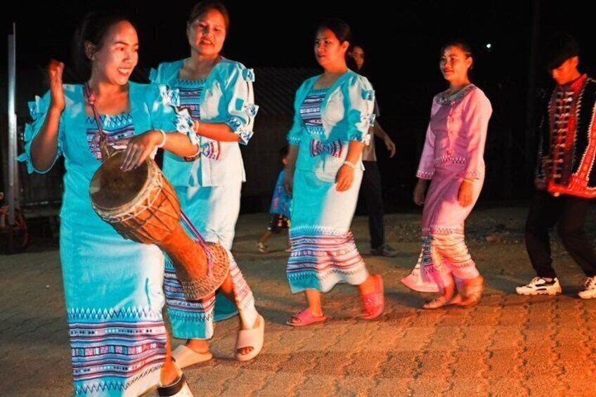 A group of people in traditional attire performing a dance, with one person playing a drum. 1