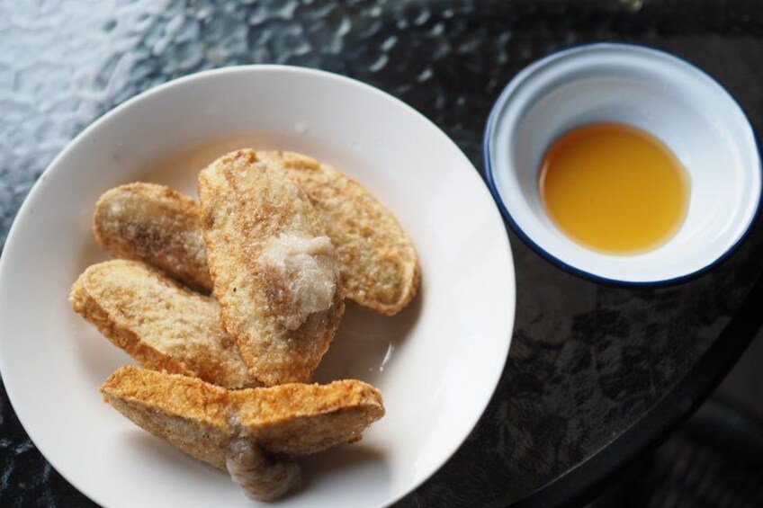 A plate of breaded and fried food items, possibly chicken, with a small bowl of egg beside it. 2