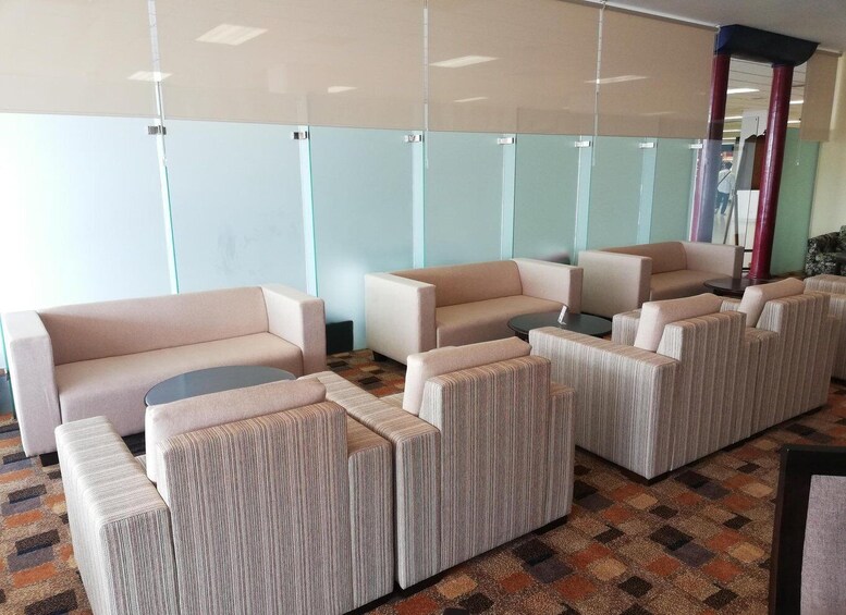 A modern waiting area with sofas and armchairs, a patterned carpet, and a glass partition wall. 5