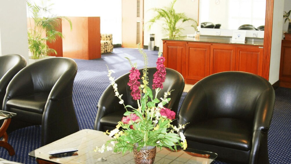 A conference room with a table, chairs, a vase with flowers, and a reception desk in the background. 1