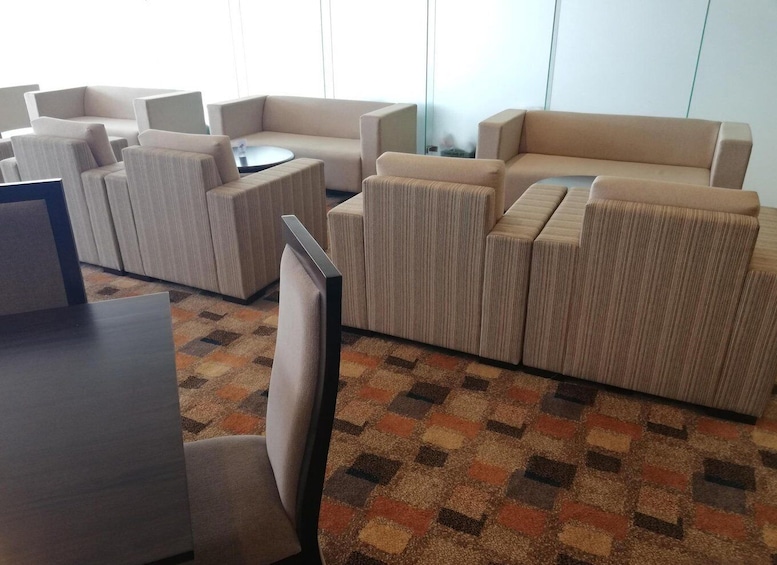 A modern living room with beige sofas, a coffee table, and a patterned carpet. 4