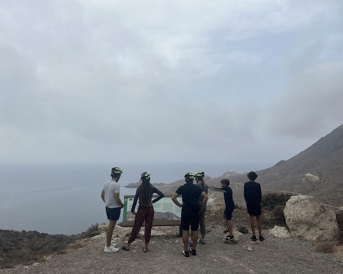 A group of people on a rocky hillside overlooking a body of water. 3