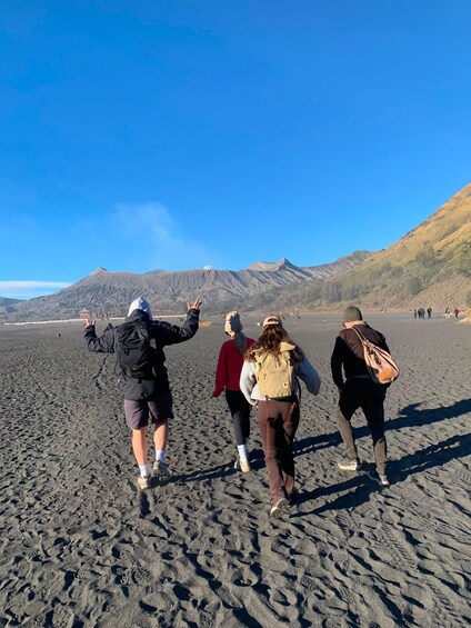 A group of people walking on a beach with mountains in the background. 3