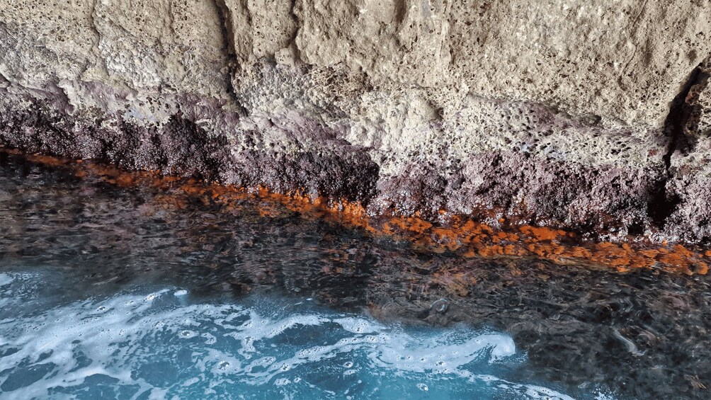 A rocky cliff with orange lichen and a flowing river. 3