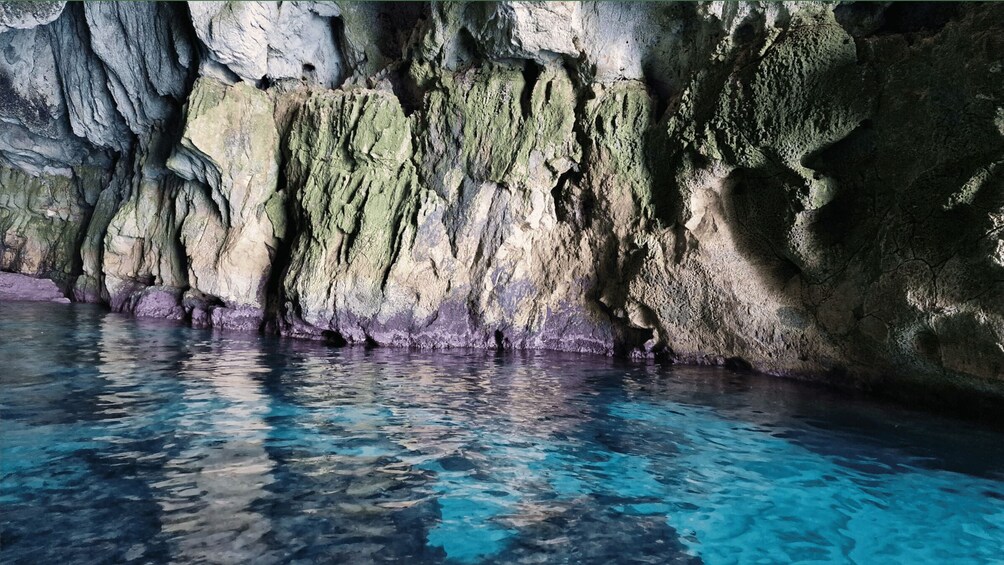 A cave with clear blue water reflecting the rocky walls. 5