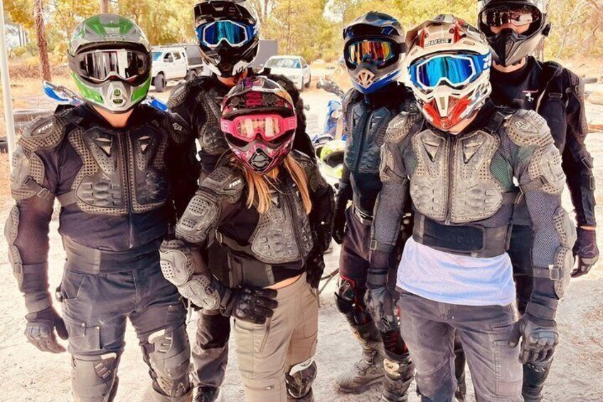 A group of people in protective gear, possibly motorcyclists, standing outdoors. 3