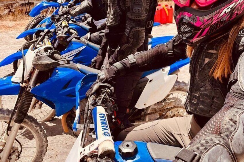 A group of dirt bikes parked on a sandy surface. 4