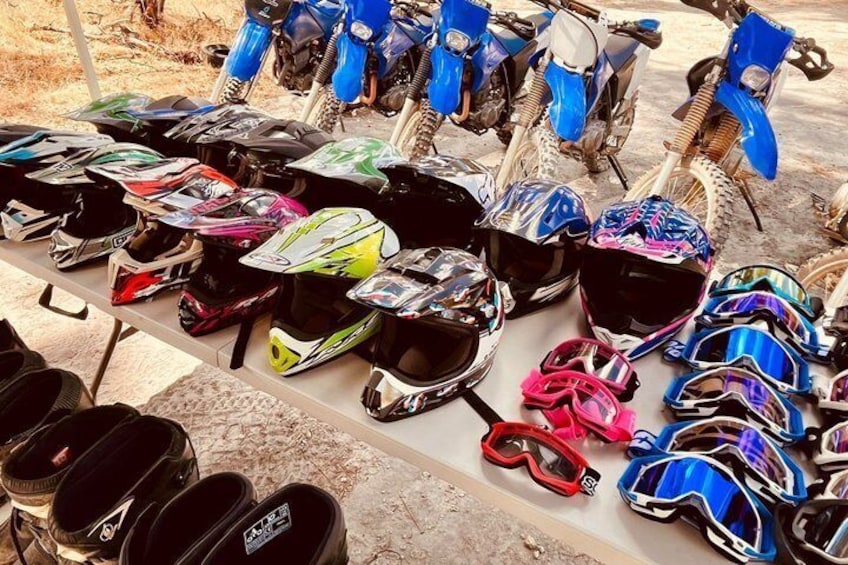 A collection of motorcycle helmets and a dirt bike on a concrete surface. 2