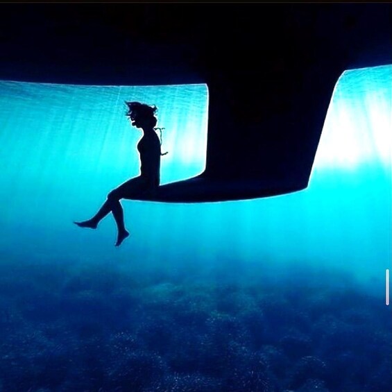 Eine Silhouette einer Person, die auf einer großen Konstruktion, möglicherweise einer Brücke, sitzt, mit blauem Unterwasserhintergrund. 3