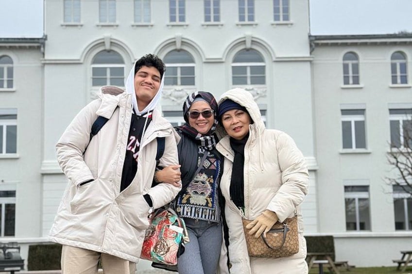 Three people standing in front of a building with arched windows. 3