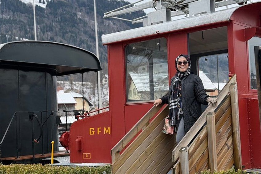 A person standing on a wooden staircase next to a red train marked 'GFM.' 4