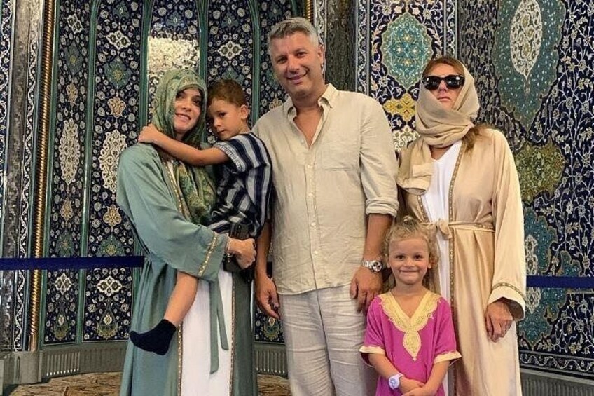 A group of people in traditional attire standing in front of a patterned wall. 5
