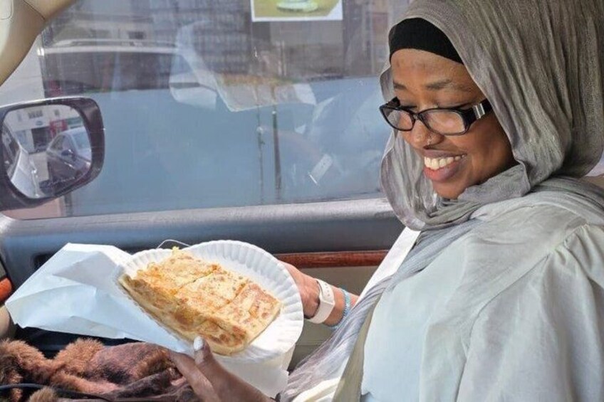 A person holding a paper plate with food, sitting in a vehicle. 4