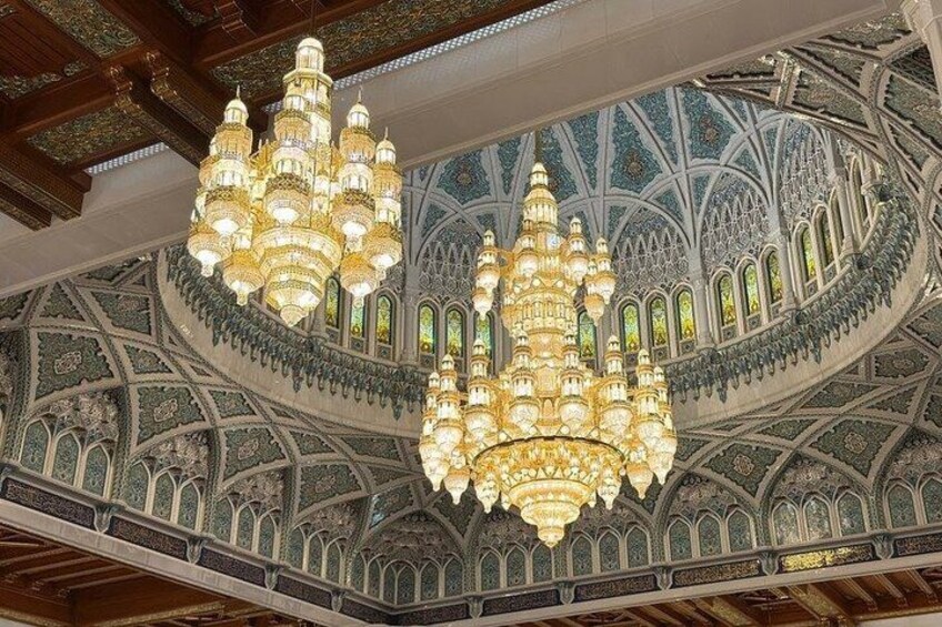 Ornate chandeliers, intricate ceiling patterns, and arched windows in a grand interior. 2