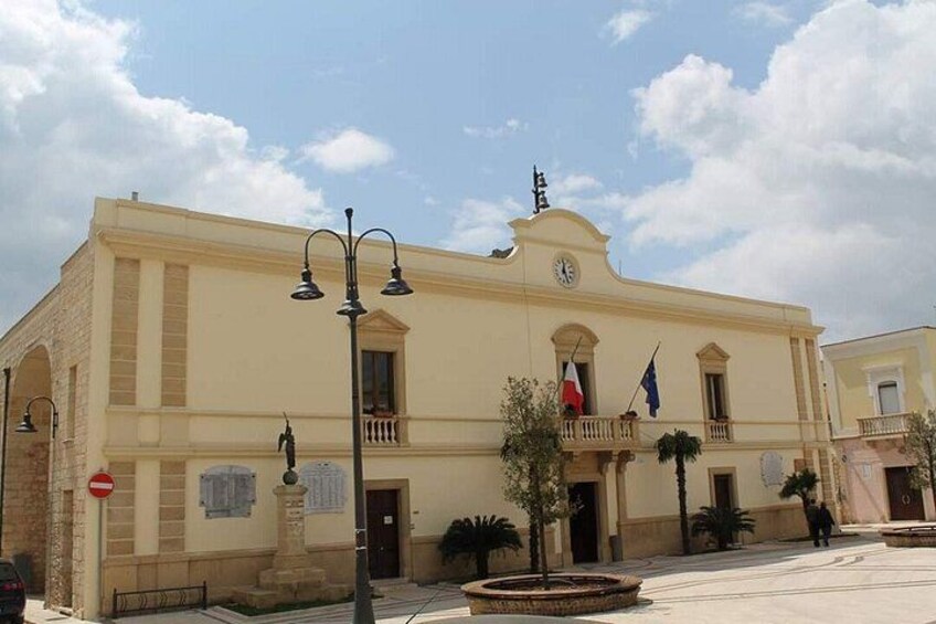 A building with a clock, flags, and a street lamp. 5