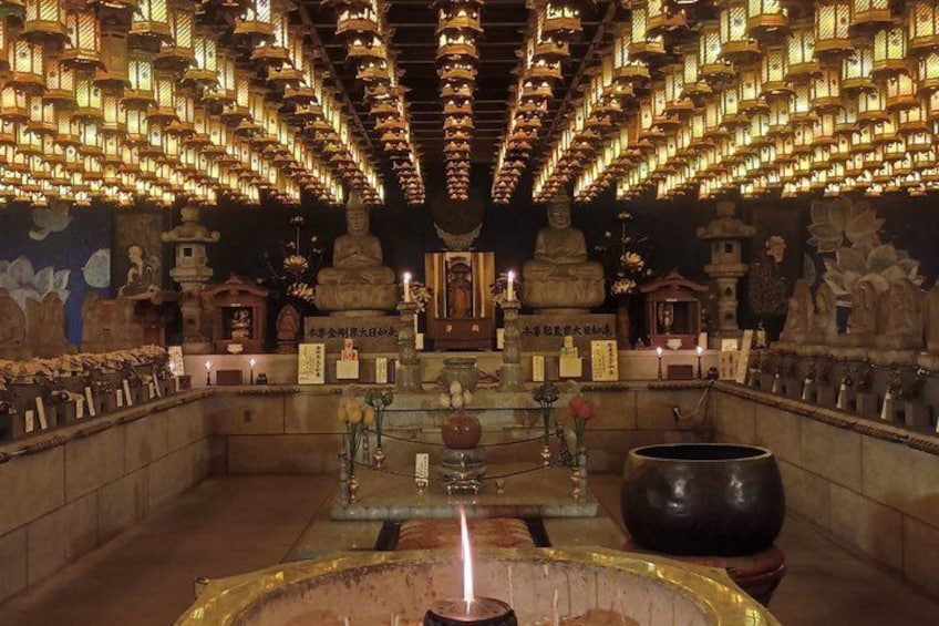 A temple interior with a central Buddha statue, lanterns, and various religious artifacts. 5