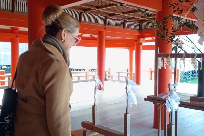 A person standing in a traditional Japanese building with red pillars and a tiled roof. 4