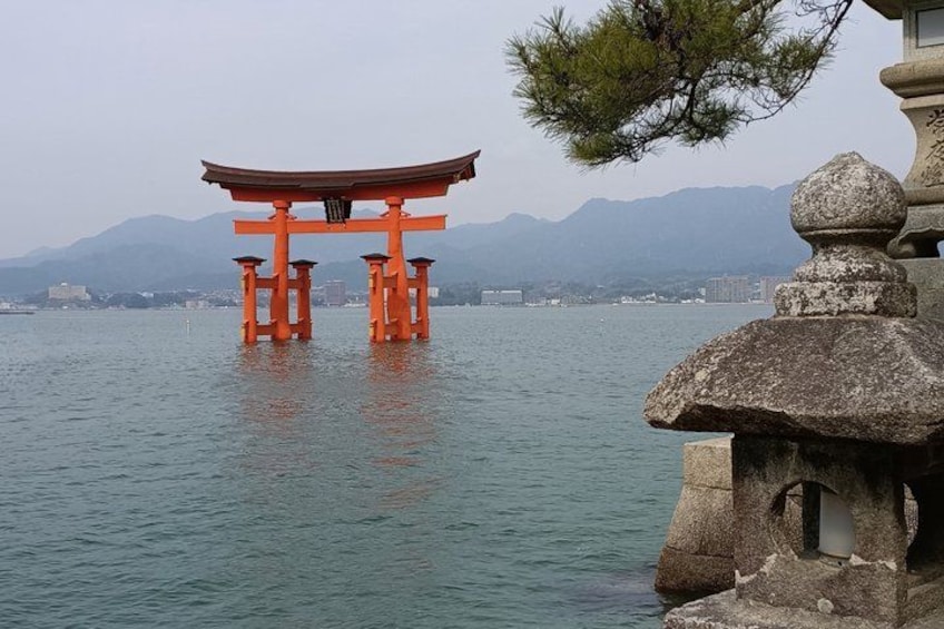 A traditional Japanese torii gate in the water, surrounded by mountains and a stone structure. 4
