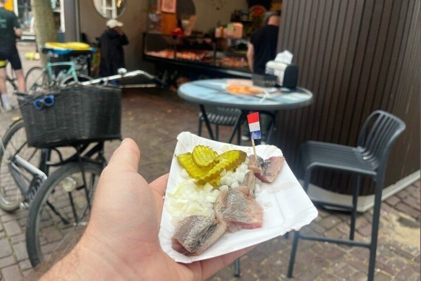A person holding a snack with pickles and a flag. 4
