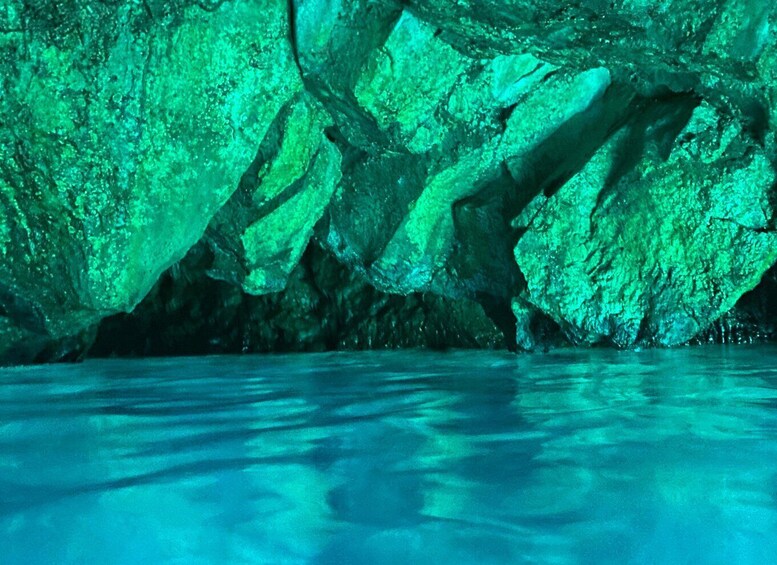 A cave with green lighting and water at the bottom. 4
