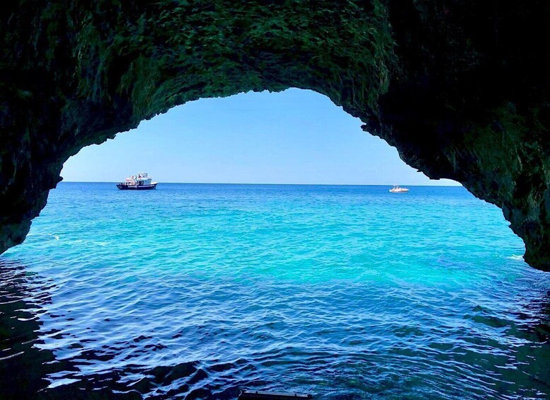 A boat in a turquoise sea through a natural arch formation. 3