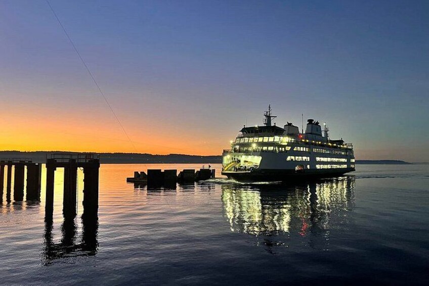 Un gran ferry al atardecer, reflejado en aguas tranquilas, con un muelle y una costa lejana. 2