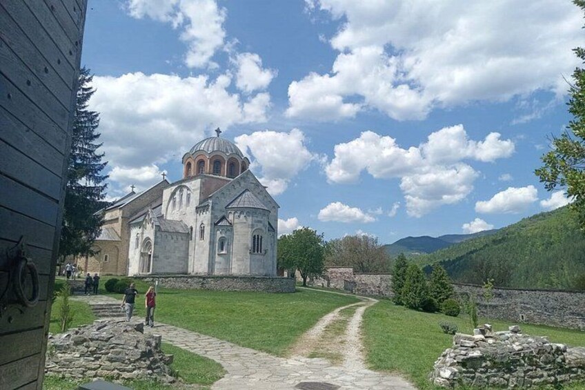 A church with a dome, a stone pathway, and a green landscape with hills in the background. 1