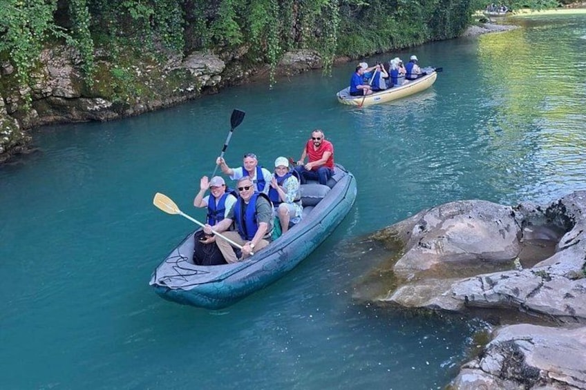 A group of people in a small boat on a river surrounded by greenery. 1