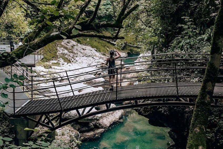 A wooden bridge over a river, surrounded by trees and rocky terrain. 5