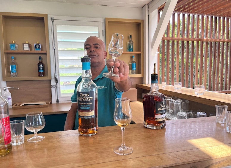 A man holding a wine glass at a bar with various bottles and glasses on the counter. 2