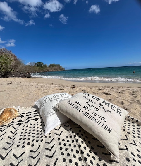 A beach with a blanket and pillows, a shell, and a clear blue sky. 1