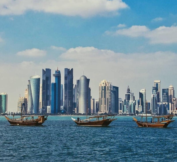 A city skyline with modern skyscrapers and three traditional boats on the water. 4
