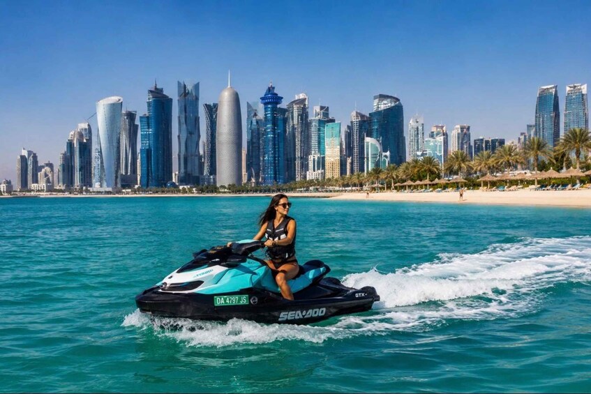 A person jet skiing on turquoise water with a city skyline in the background. 1