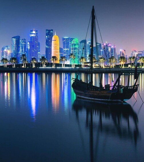 A nighttime cityscape with illuminated skyscrapers reflected in calm water, a traditional boat in the foreground, and palm trees lining the waterfront. 5