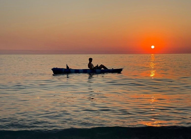 A person in a boat on calm water during sunset. 1