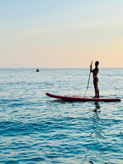 A person paddleboarding on a calm sea with a clear sky. 5