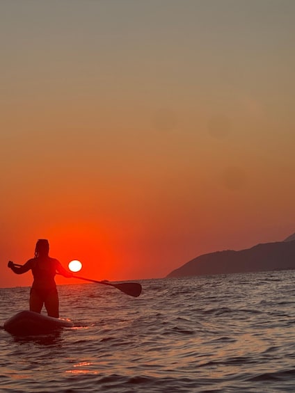 A person kayaking at sunset with a mountain in the background. 3