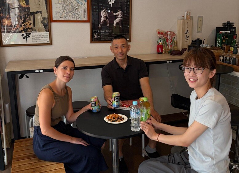 Three people sitting at a table with drinks and snacks. 5