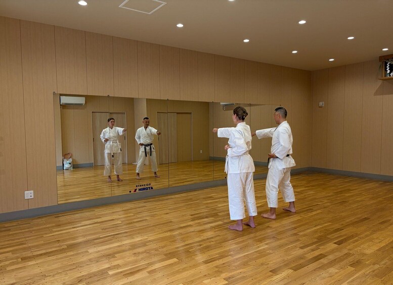 A martial arts training room with wooden floors and mirrored walls. 2
