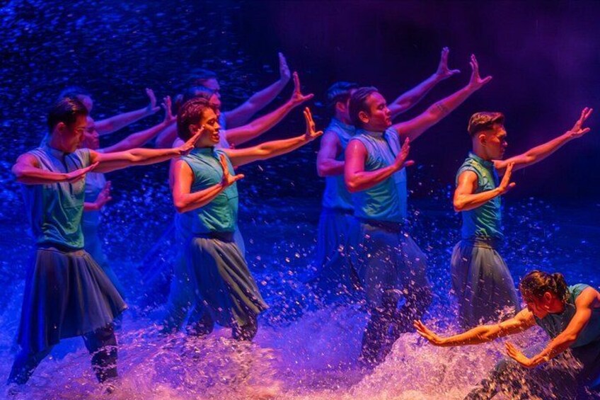 A group of dancers performing on a stage with a water effect. 4