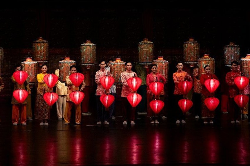 A group of people in traditional attire holding red lanterns on a stage with ornate lanterns in the background. 5