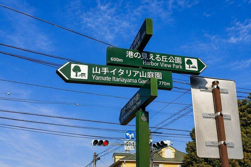 A directional signpost with multiple green signs pointing to various destinations including Harbor View Park and Yamate Itaria Yama Garden. 4