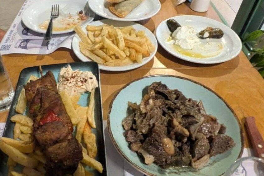 A table with various dishes including meat, fries, and a plate with a dollop of sauce. 3