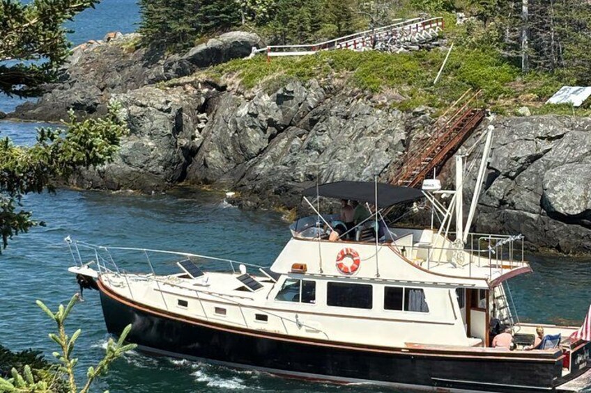 A boat docked near rocky shores with a lifebuoy and an American flag. 2