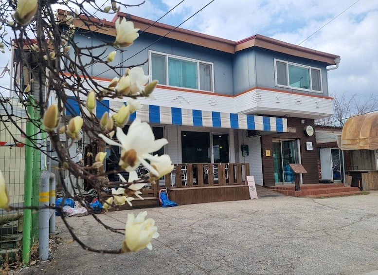 A two-story building with a blue and white facade, a wooden deck, and a signboard. 3