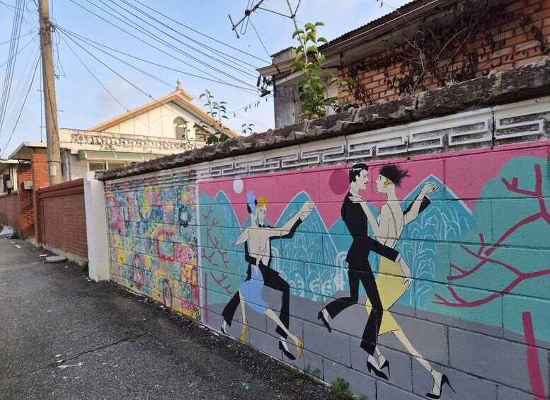 A colorful mural on a wall depicting two figures dancing. 2