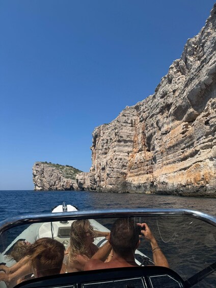 A boat with passengers enjoying a coastal view. 1