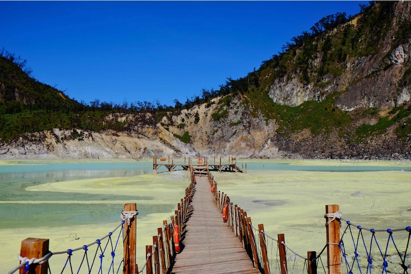 A wooden boardwalk leading to a dock over a calm, turquoise lake with a mountainous backdrop. 1