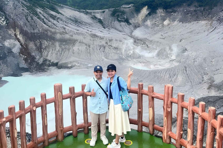Two people standing on a wooden fence with a volcanic landscape in the background. 3