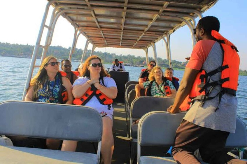 A group of people on a boat with life jackets, a covered upper deck, and calm water. 2